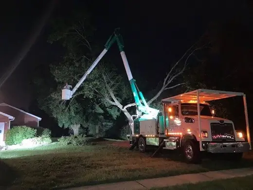 Countryside Tree Experts bucket truck lit up at night working a residential tree after storm damage