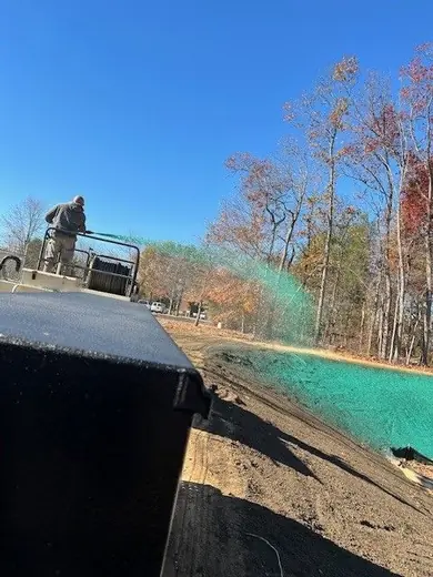 Green hydroseed slurry being sprayed across freshly graded ground