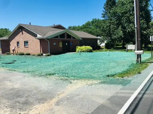The same commercial building lot after hydroseeding, with an established green lawn