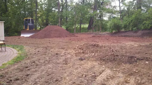 Bulldozer grading a residential backyard before the work is finished